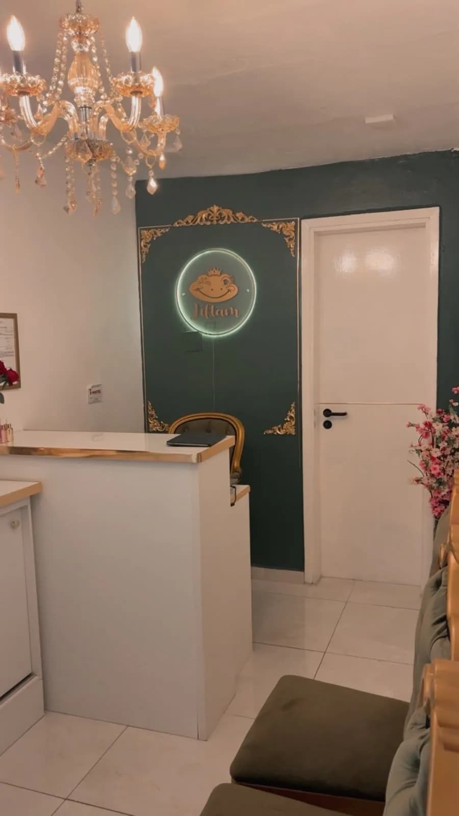 Recepção da Liftam com lustre de cristais e o logo em neon sobre parede verde